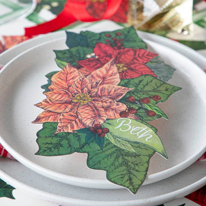 Close-up view of the Poinsettia Table Accent with &quot;Beth&quot; written on the leaf in cursive, resting on Salt Dinner Plates.