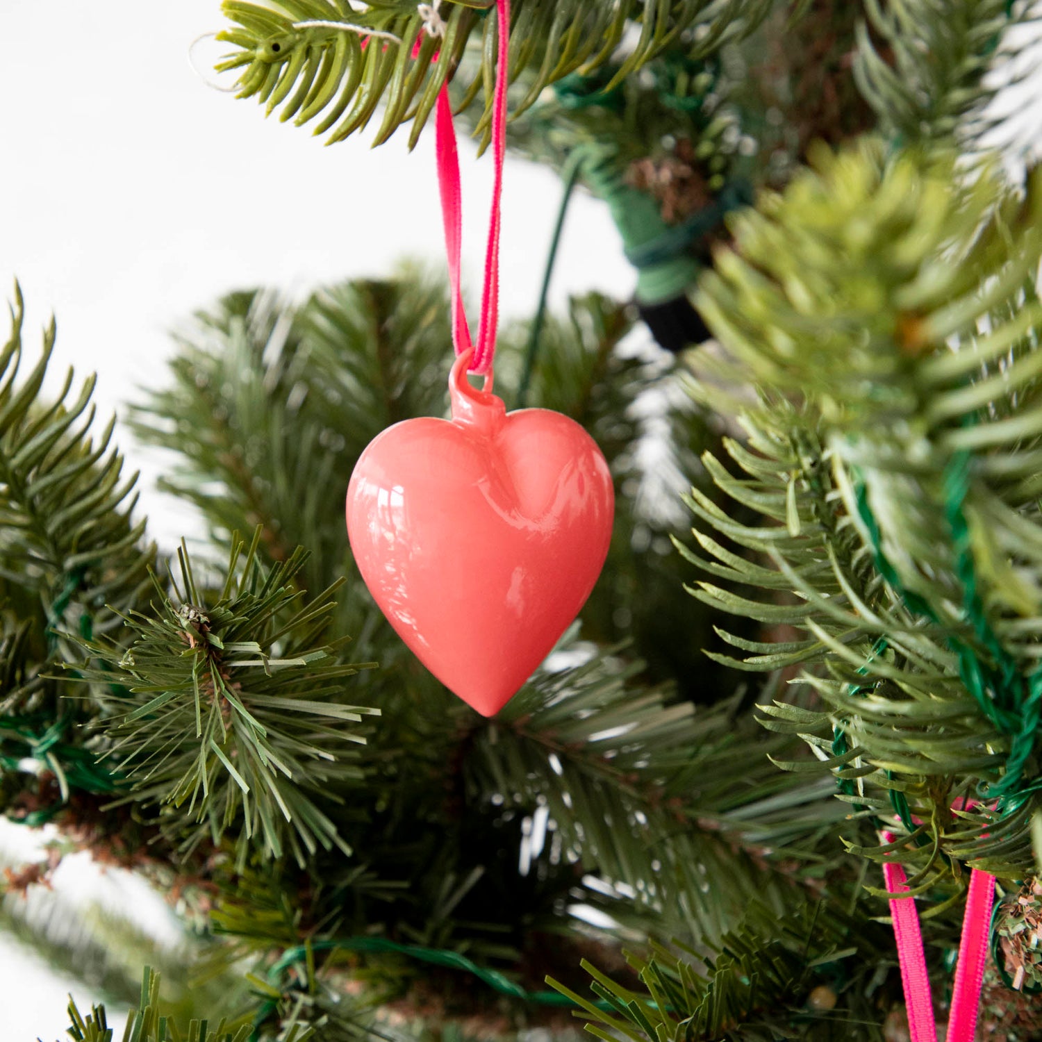 Vibrant Glitterville heart ornaments hanging on a Christmas tree.