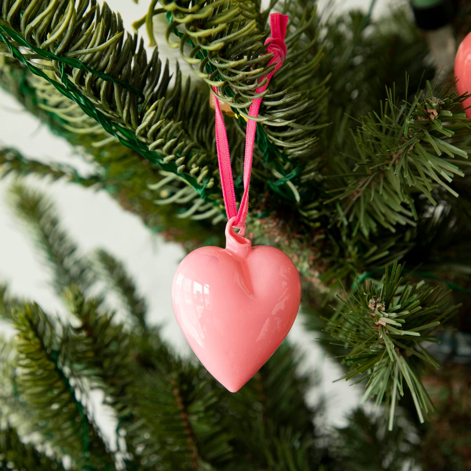 Vibrant Glitterville heart ornaments hanging on a Christmas tree.