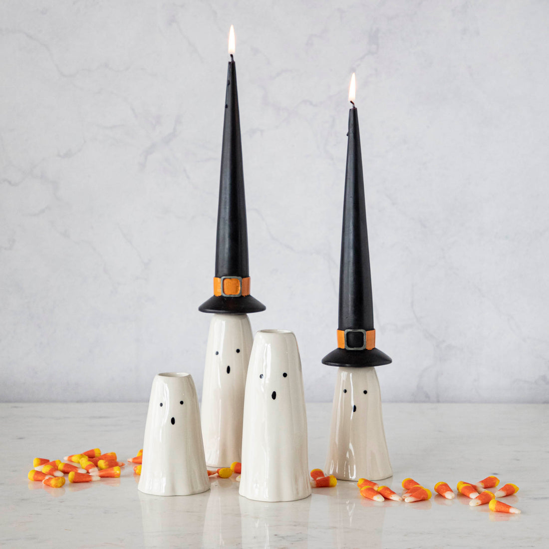 Four Phantom Candleholders from Accent Decor with witch hat candles, on a table surrounded by candy corn.