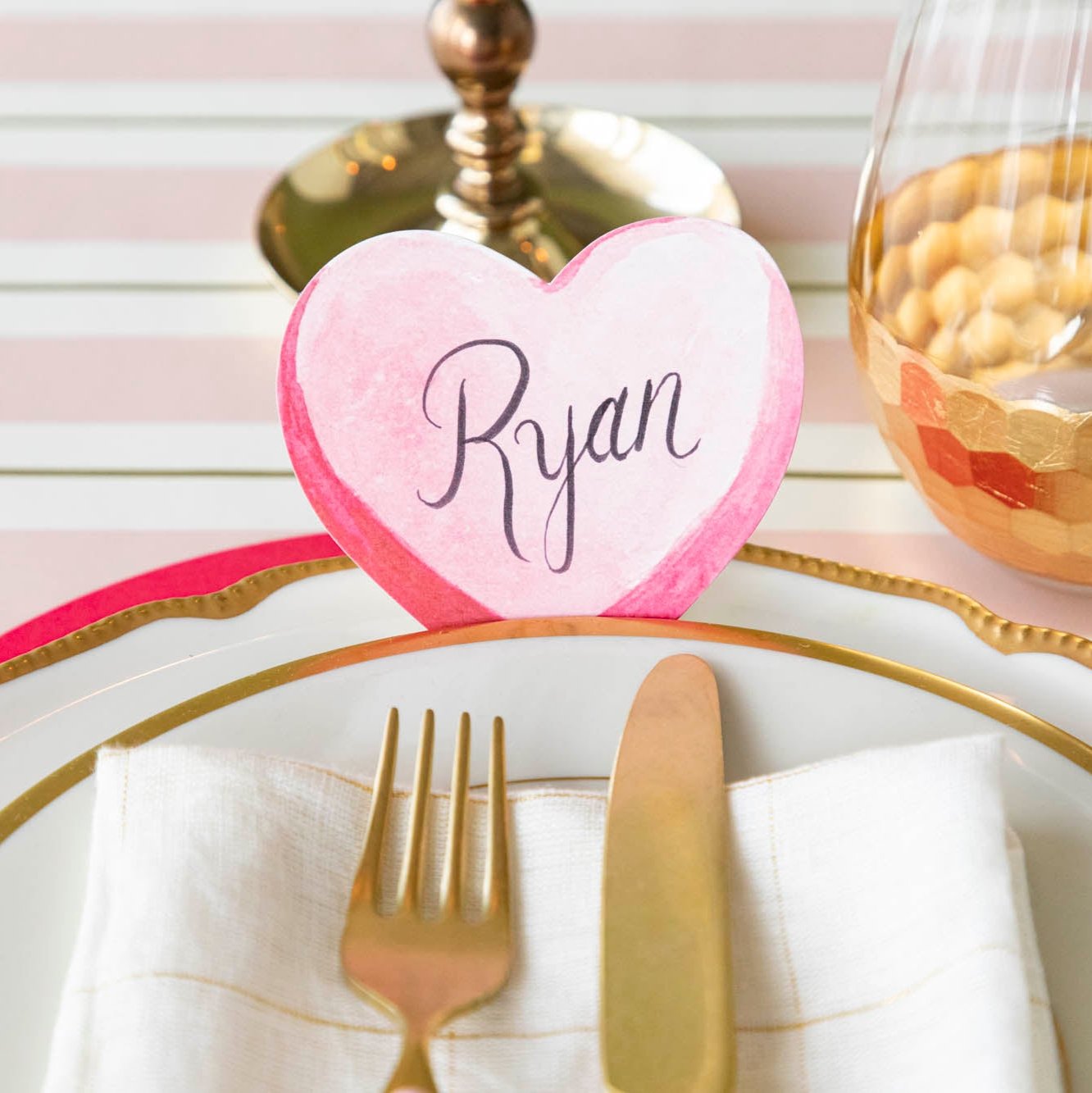 The Conversation Heart Place Card with "Ryan" written on it, behind elegant plates.