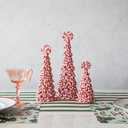 Three assorted sizes of peppermint trees on a table with peppermint themed holiday table setting.