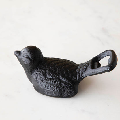 A small Park Hill Cast Iron Bird Bottle Opener with a rustic cast iron finish is sitting on a table.