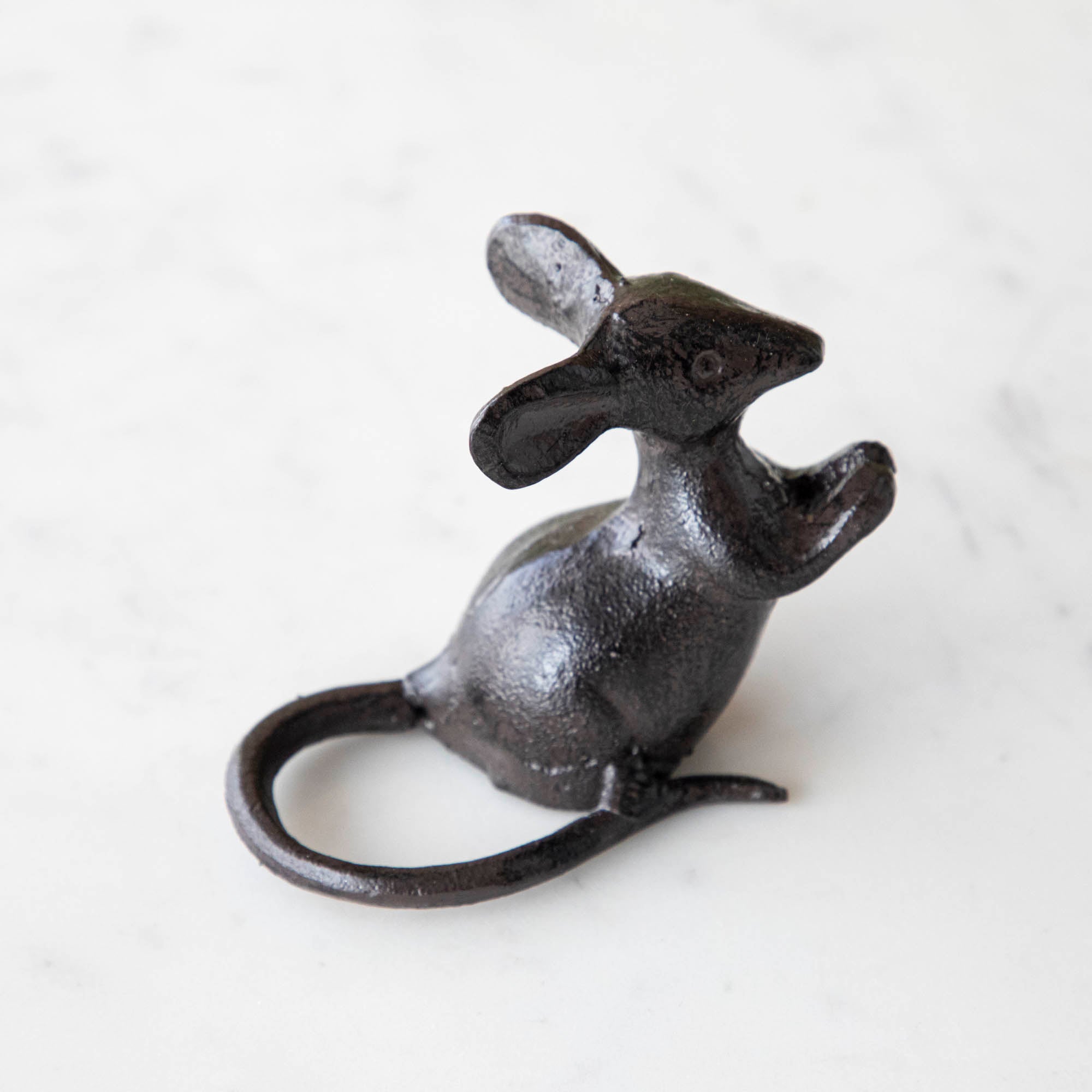Two cast iron black mice on a marble board with cheese.
