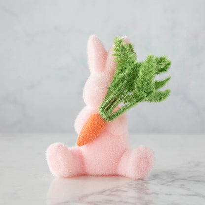 A Glitterville flocked pink bunny holding a bunch of carrots, perfect for Easter.