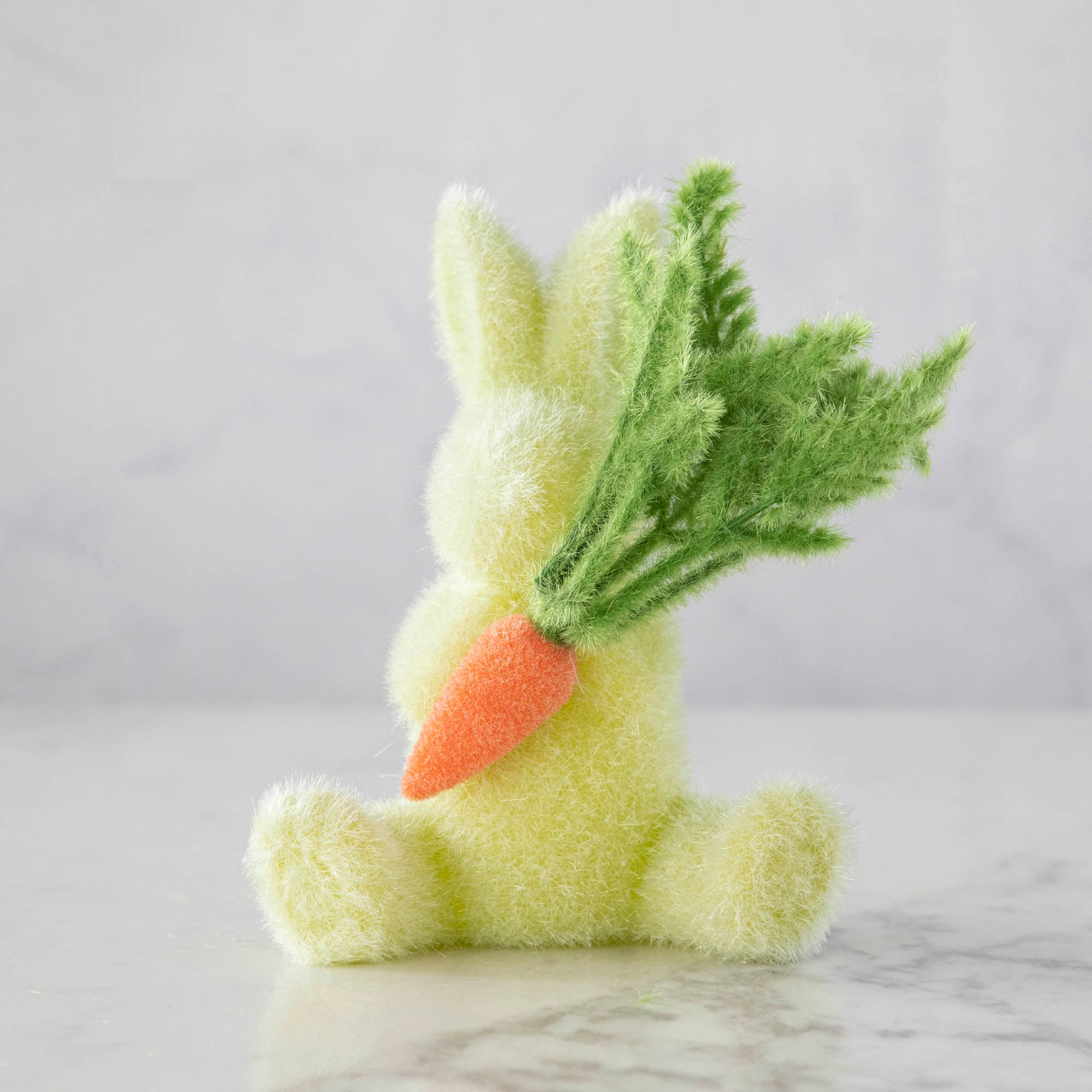 A Glitterville Flocked Bunny with Carrot on a table, perfect as an Easter decoration or for the spring season.