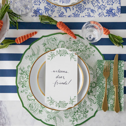 A table setting with a blue and white striped tablecloth and carrots, featuring Green Calico Napkins by Hester &amp; Cook.