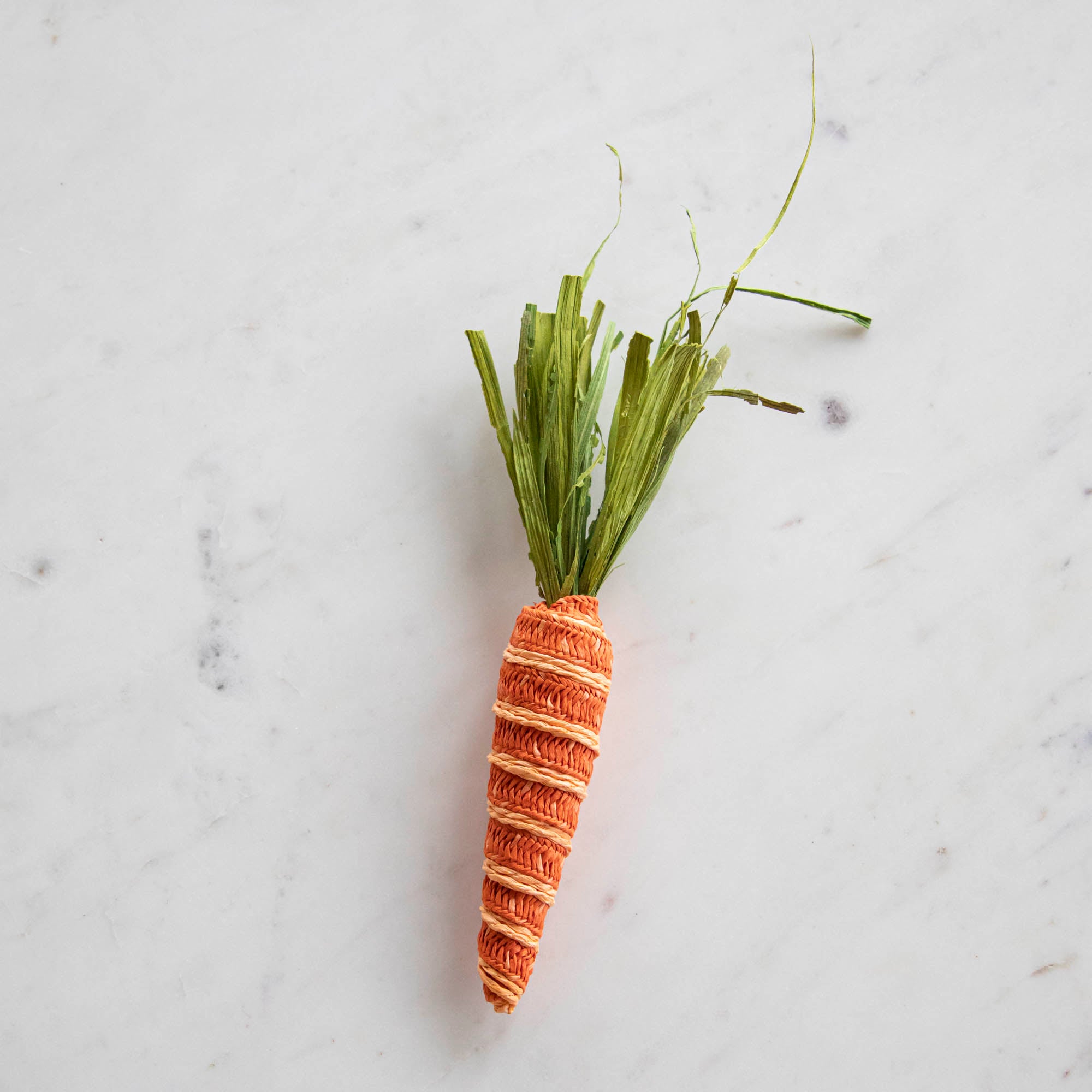 A Glitterville knitted Natural Carrot on a marble surface, perfect for Easter baskets or table settings.