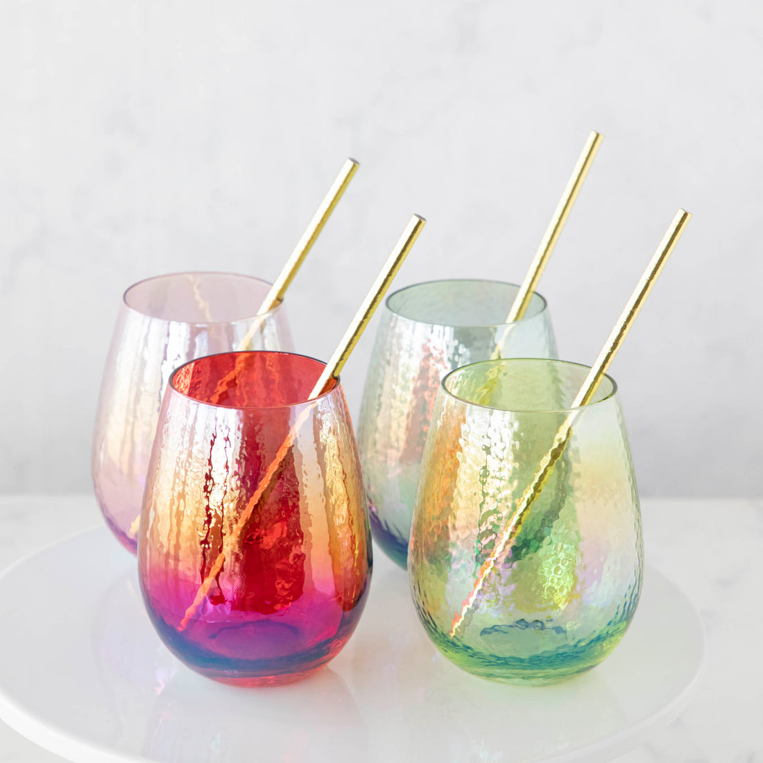 Four Luster Stemless Glassware with gold straws on a white plate, perfect for home drinks by Zodax.