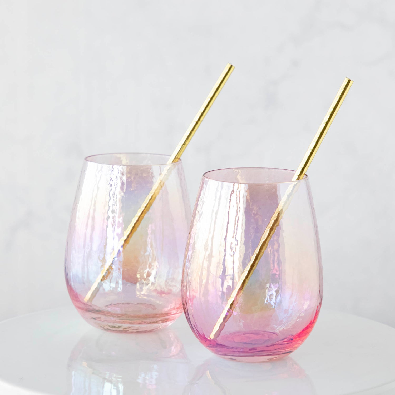 Two Luster Stemless Glassware with gold straws on a white table. (Zodax)