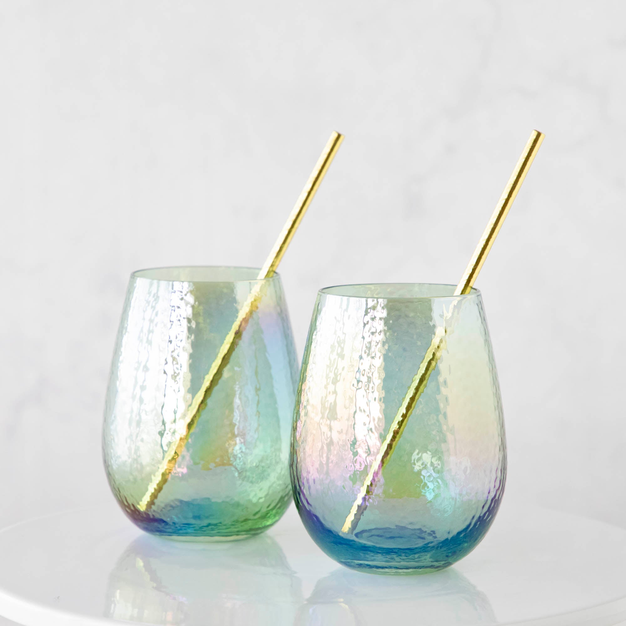 Two Luster Stemless Glassware with gold straws on a white table at home. (Zodax)
