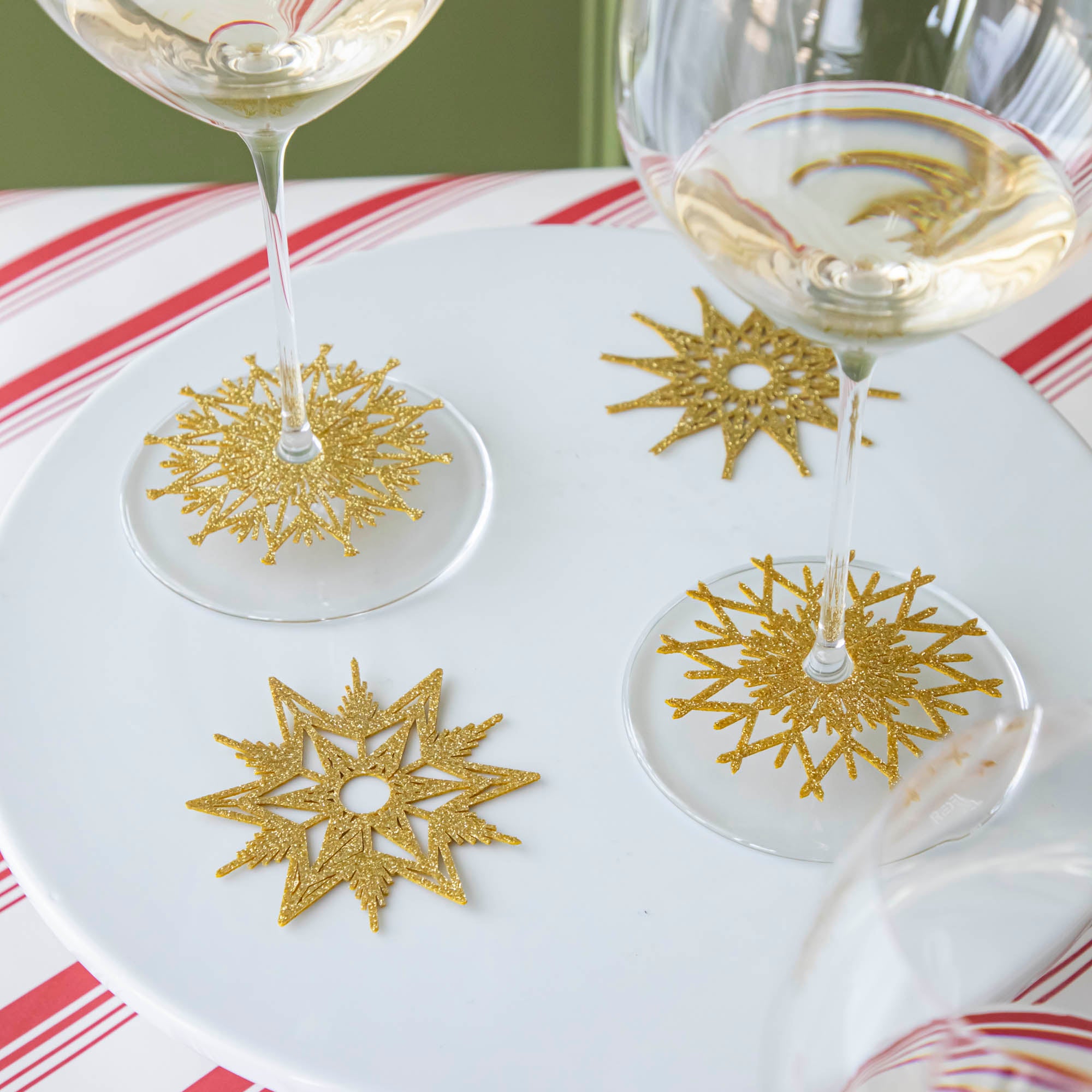 Two wine glasses with assorted Stemware Snowflake Collars and two collars resting on the cake plate beside them.