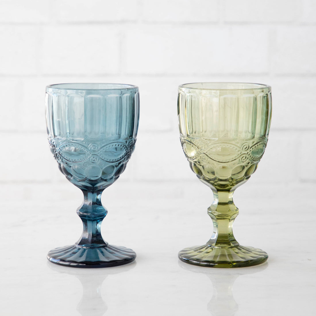 Two Momento Coupe Glasses by Accent Decor sitting on top of a white plate in a vintage style.