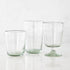 Three empty Margarida Recycled Glasses vessels of varying heights and shapes, made by Casafina Living, rest on a white surface.