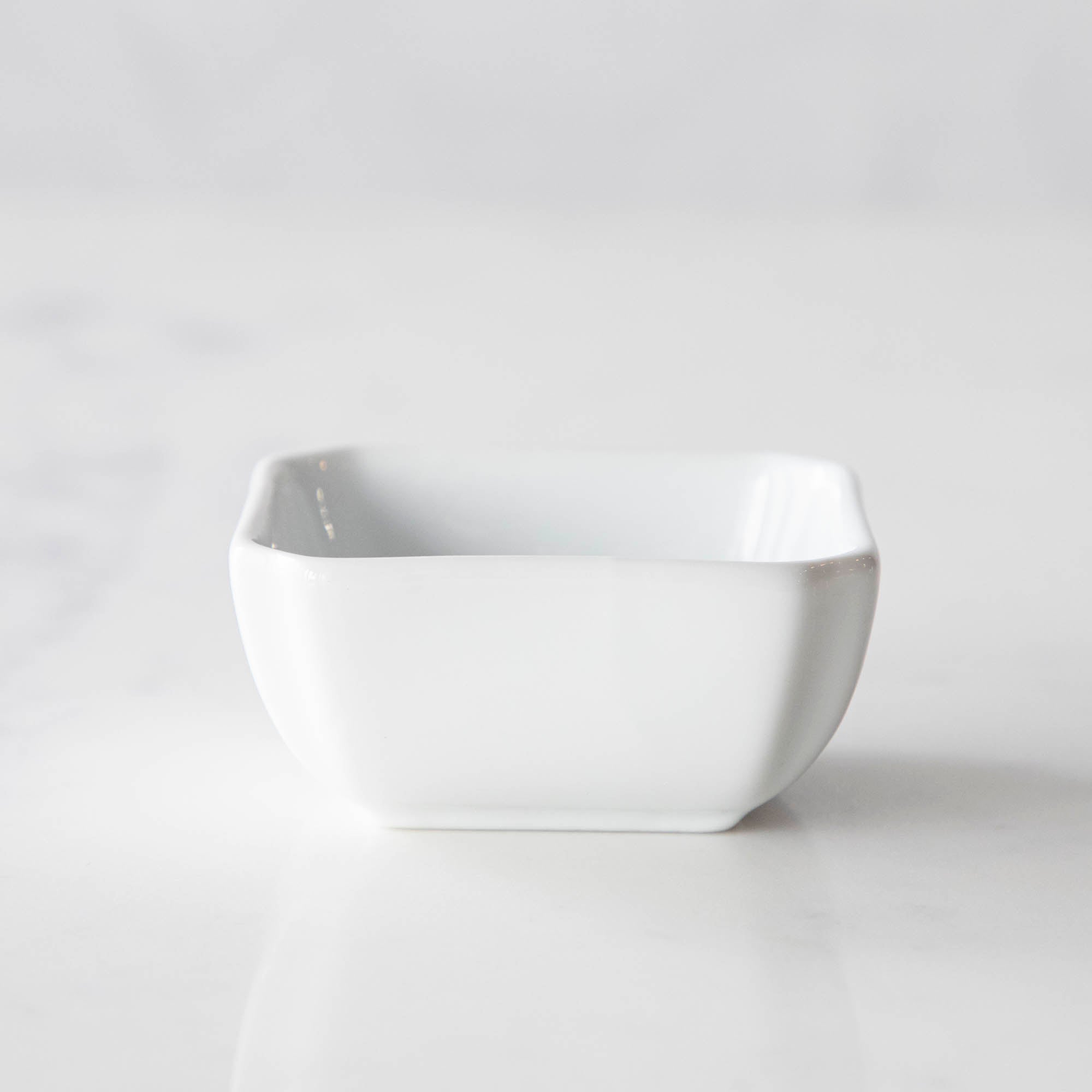 Three White Porcelain Mini Bowls with assorted spices and a spoon on a marble surface by BIA.