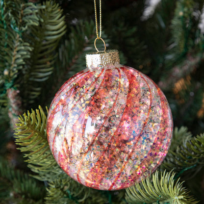 Orange &amp; White Candy Striped Glitter ball ornament hanging in a tree