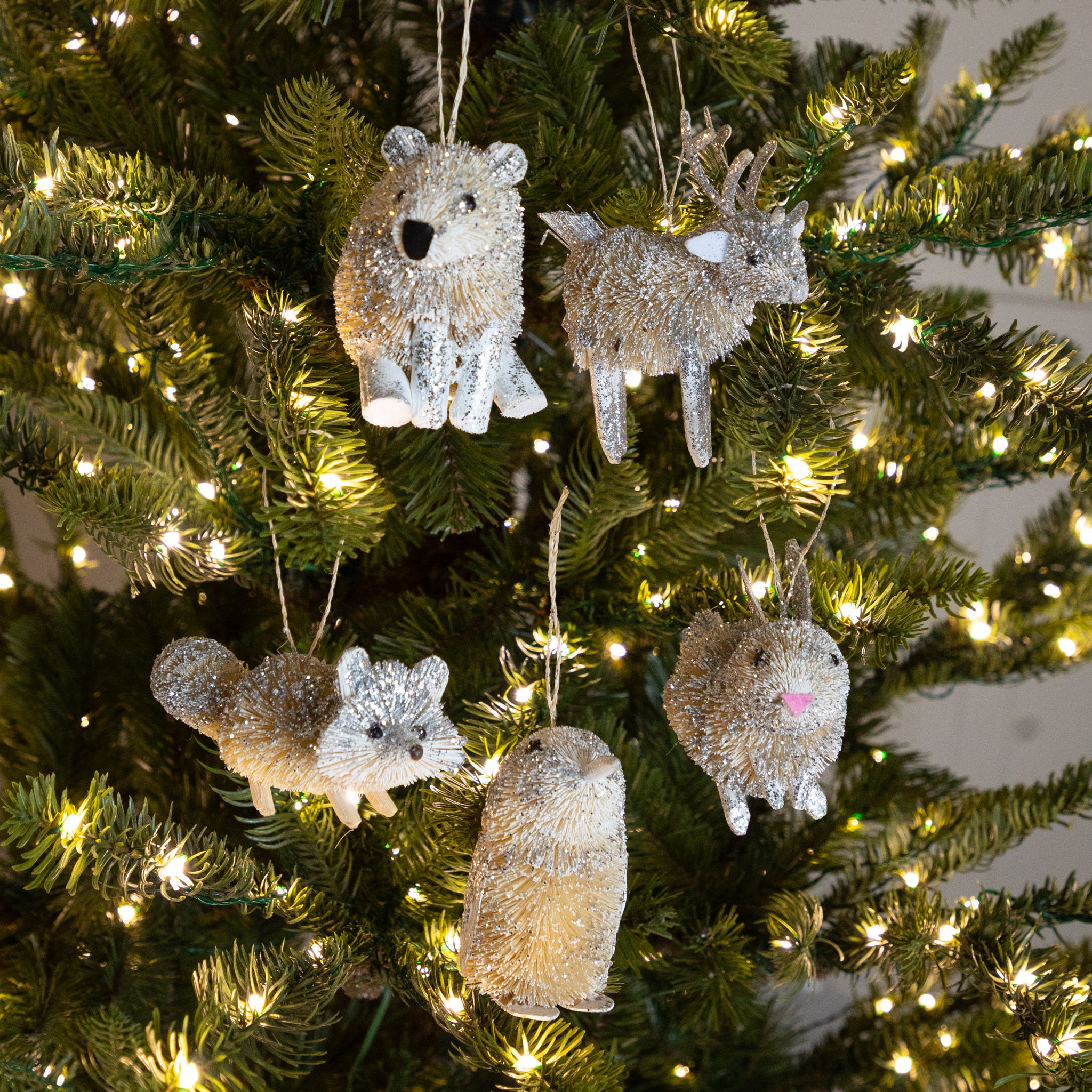 Decorative animal ornaments on a Christmas tree with lights.