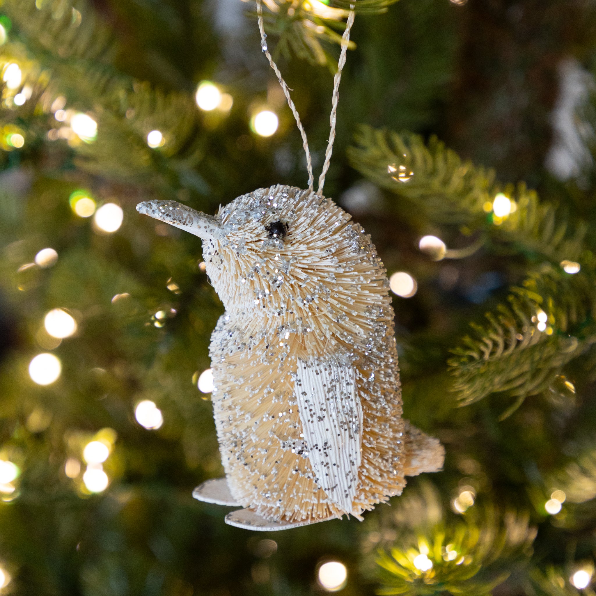 Decorative penguin ornament on a Christmas tree with lights.