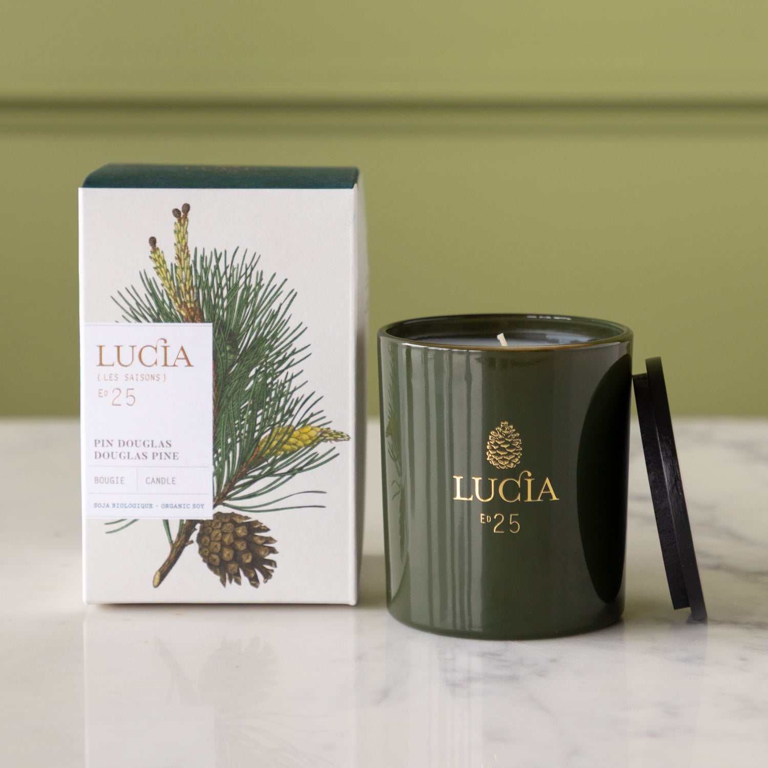 Green Lucia candle and packaging on a marble surface with a green background