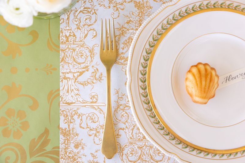 Elegant table setting with gold fork, decorative plates, and floral elements.