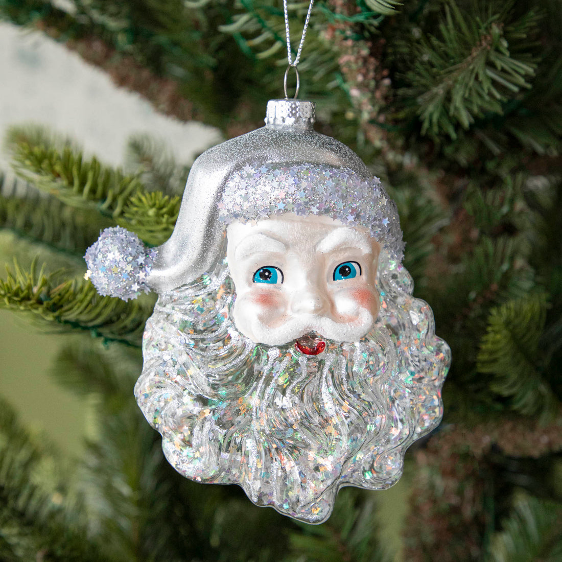 5&quot; Glass santa ornament featuring a silver glittered beard, a silver star glittered hat and bright blue eyes, hanging from a silver string.