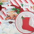 A decorative plate featuring a Santa Claus design with a red and white striped background, a white and red Christmas stocking, and a name &