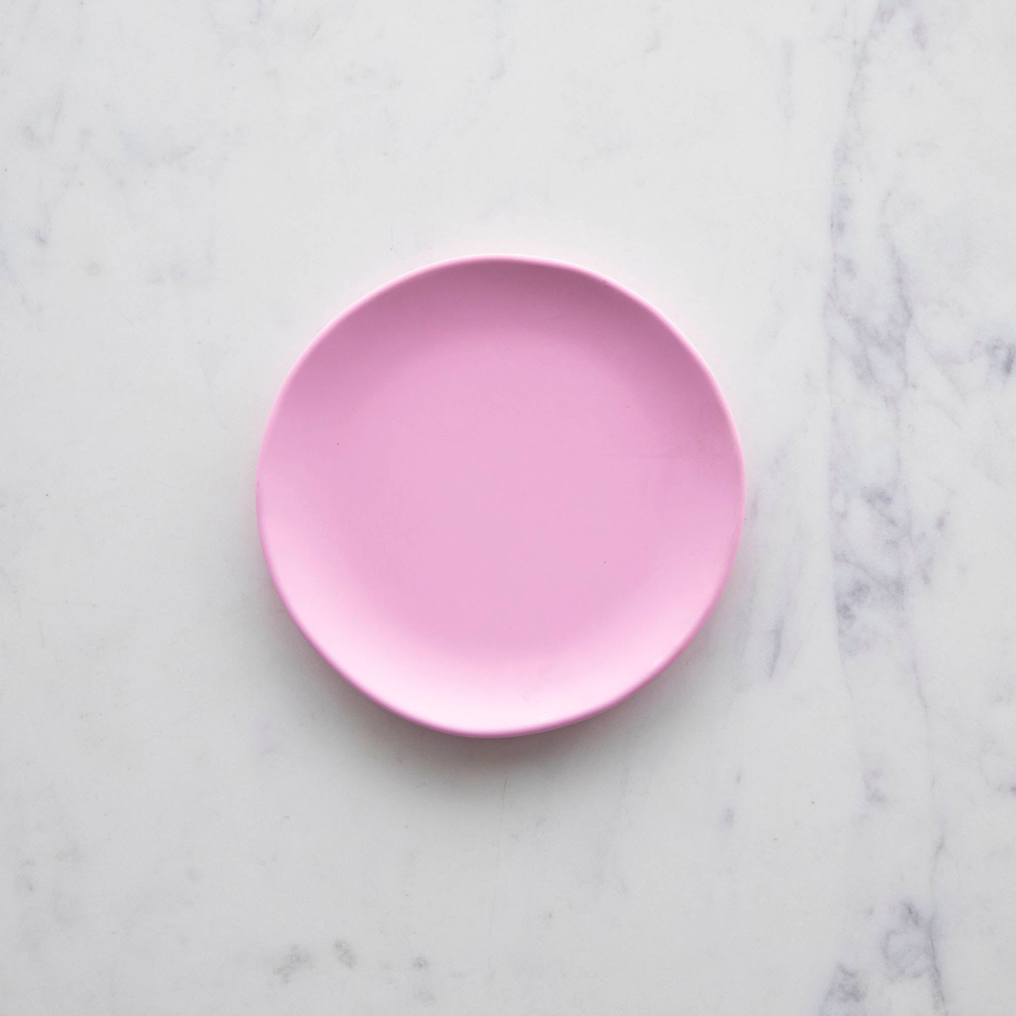 A 6&quot; macaron Rainbow Melamine Plate by Glitterville on a marble surface.