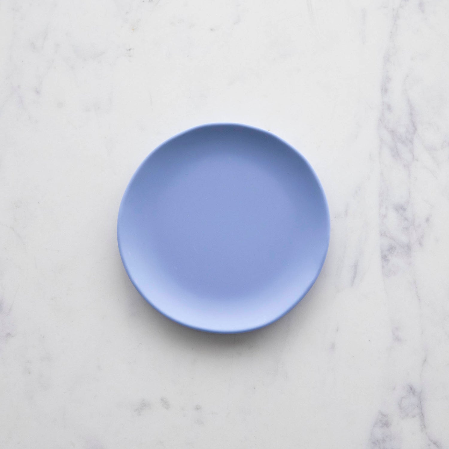 A 6&quot; huckleberry blue Rainbow Melamine Plate from Glitterville on a marble surface.
