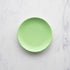 A 6" Lime Rainbow Melamine Plate by Glitterville on a marble surface.