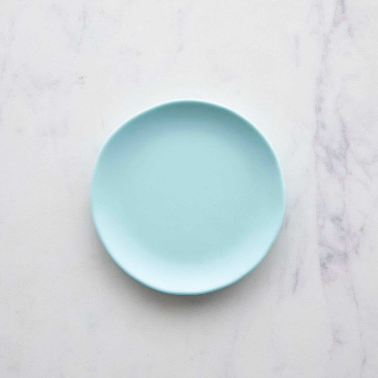 A 6&quot; Rainbow Melamine Plate by Glitterville on a marble surface.
