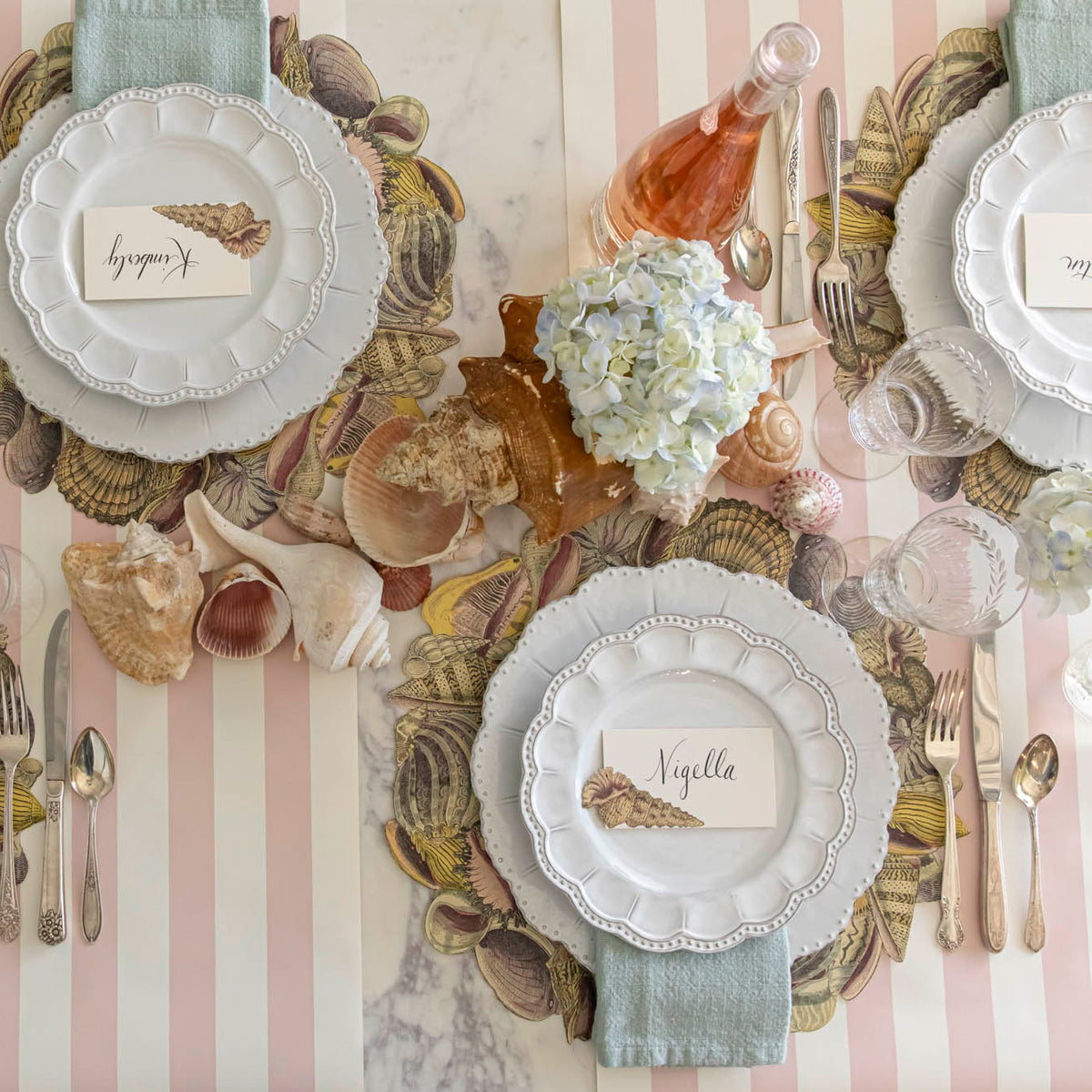 Die-cut Shell Wreath Placemat under a place setting for two, on a shell themed table.