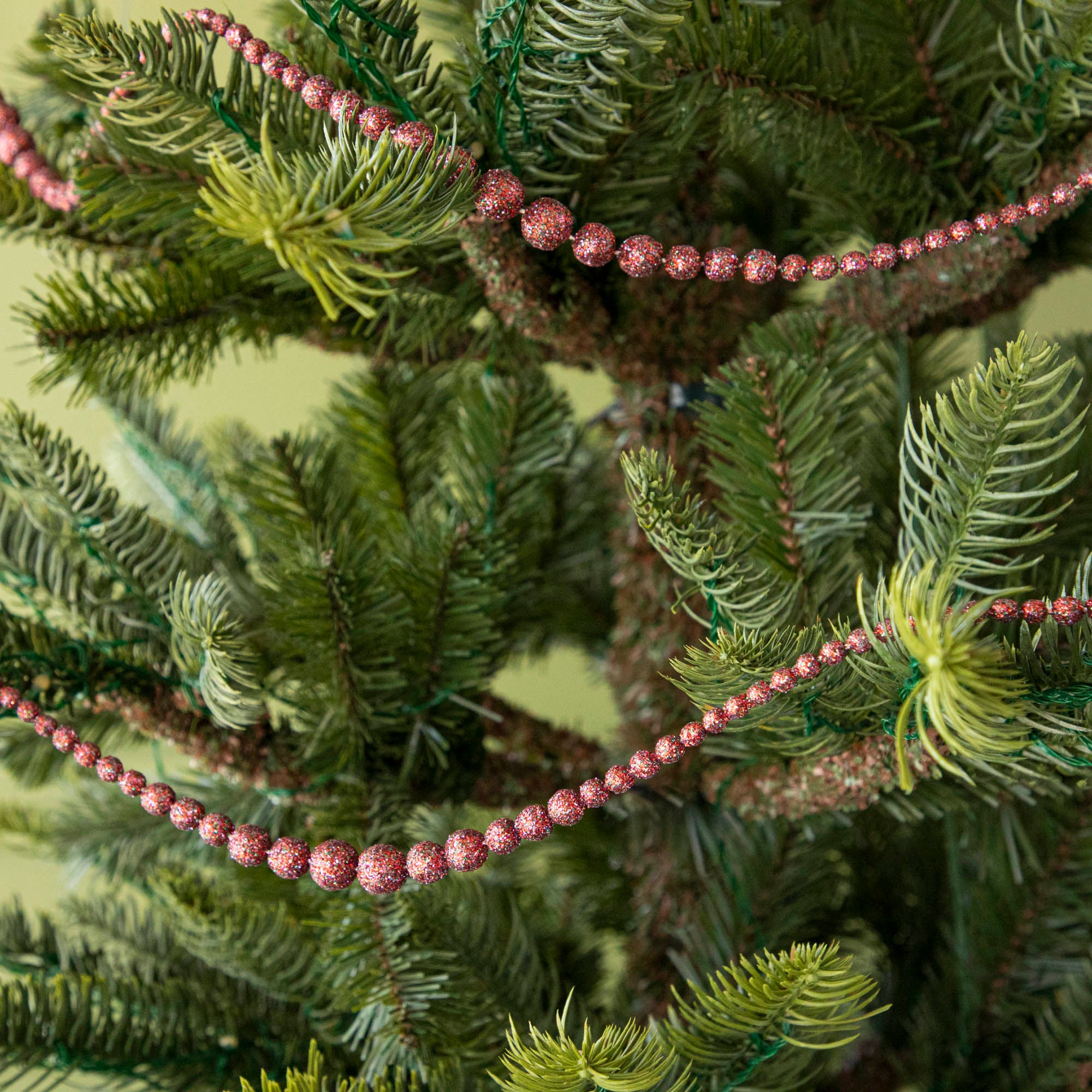 red sparkly ball garland hanging in a tree