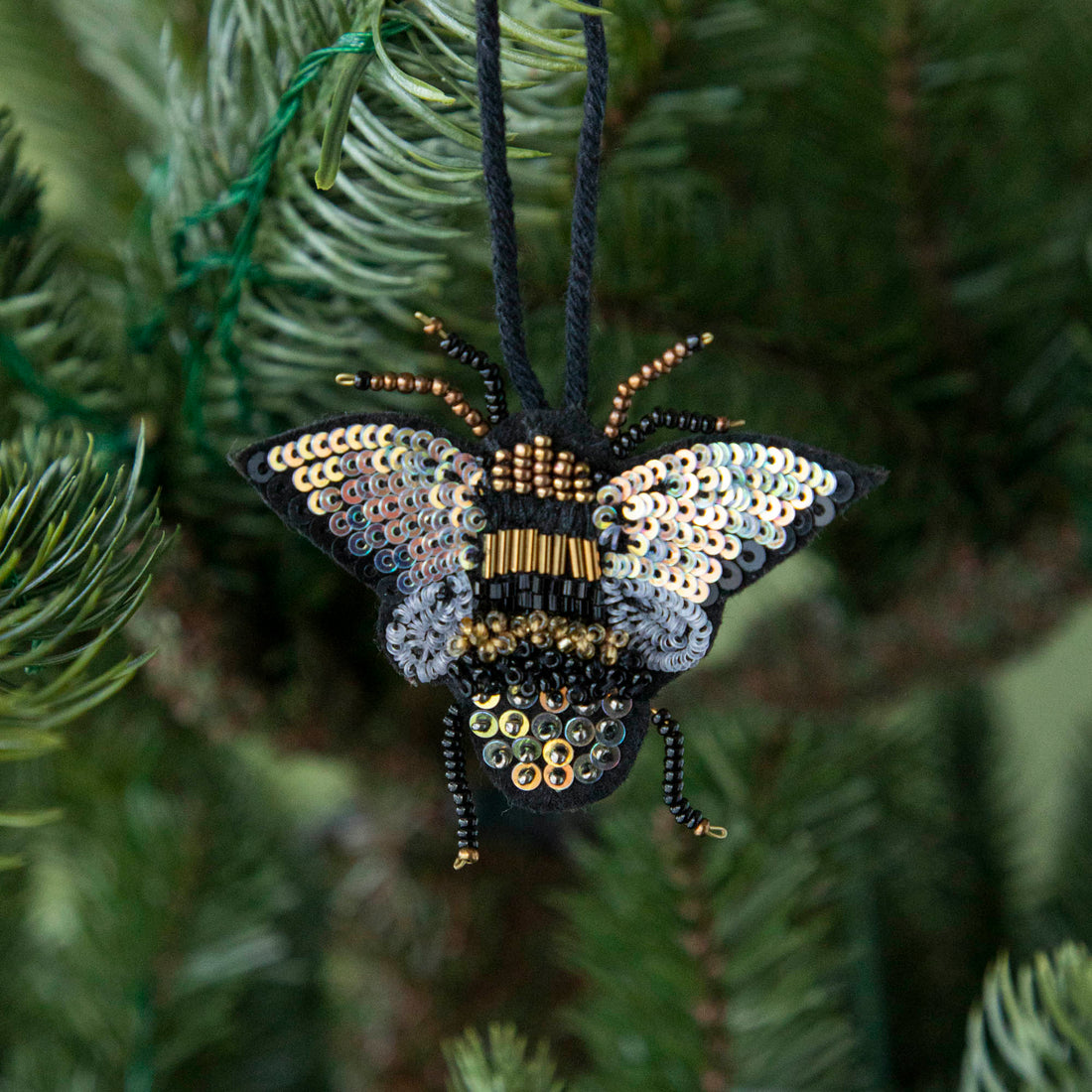 Sequin bee ornament hanging in a tree