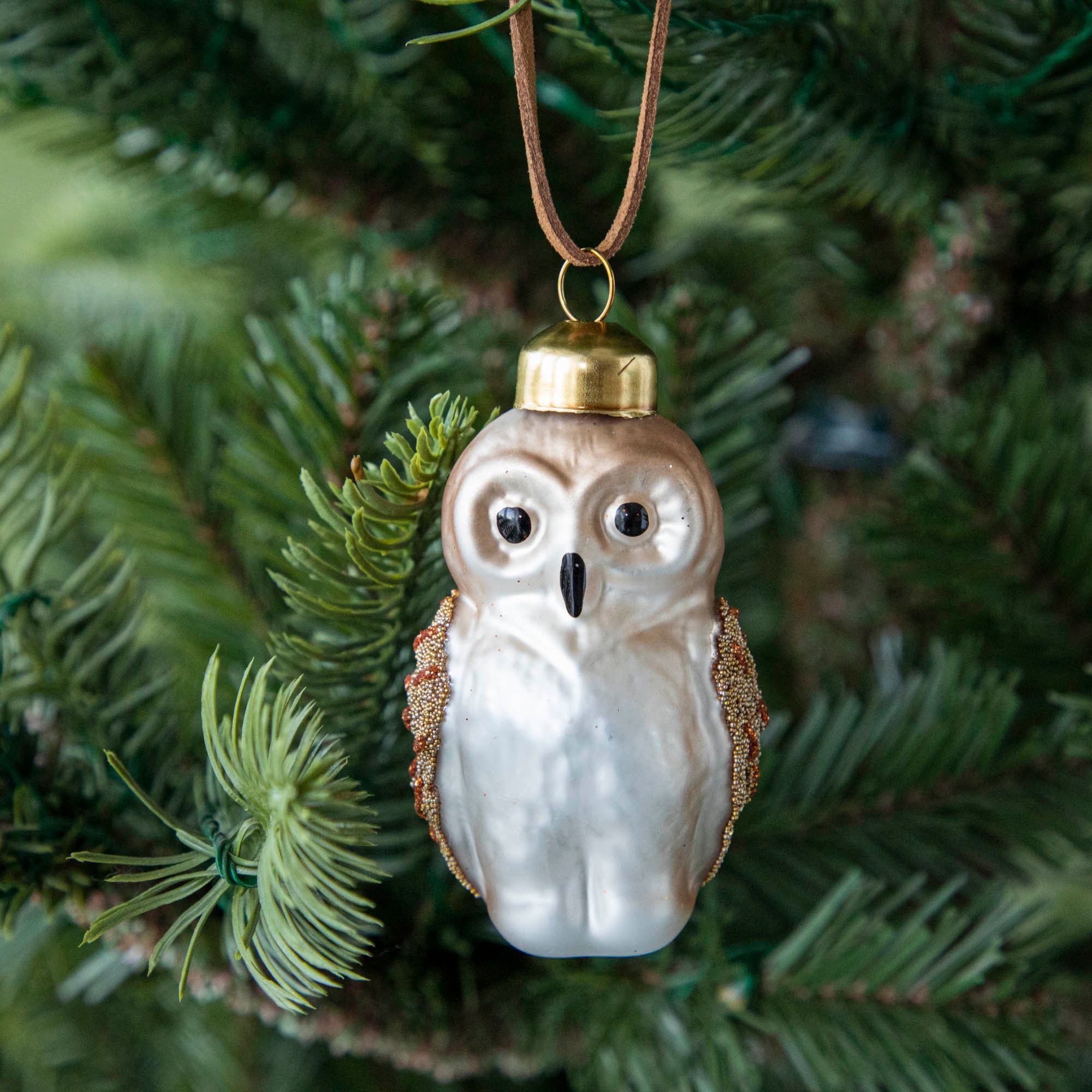 Glass owl ornament hanging in a tree