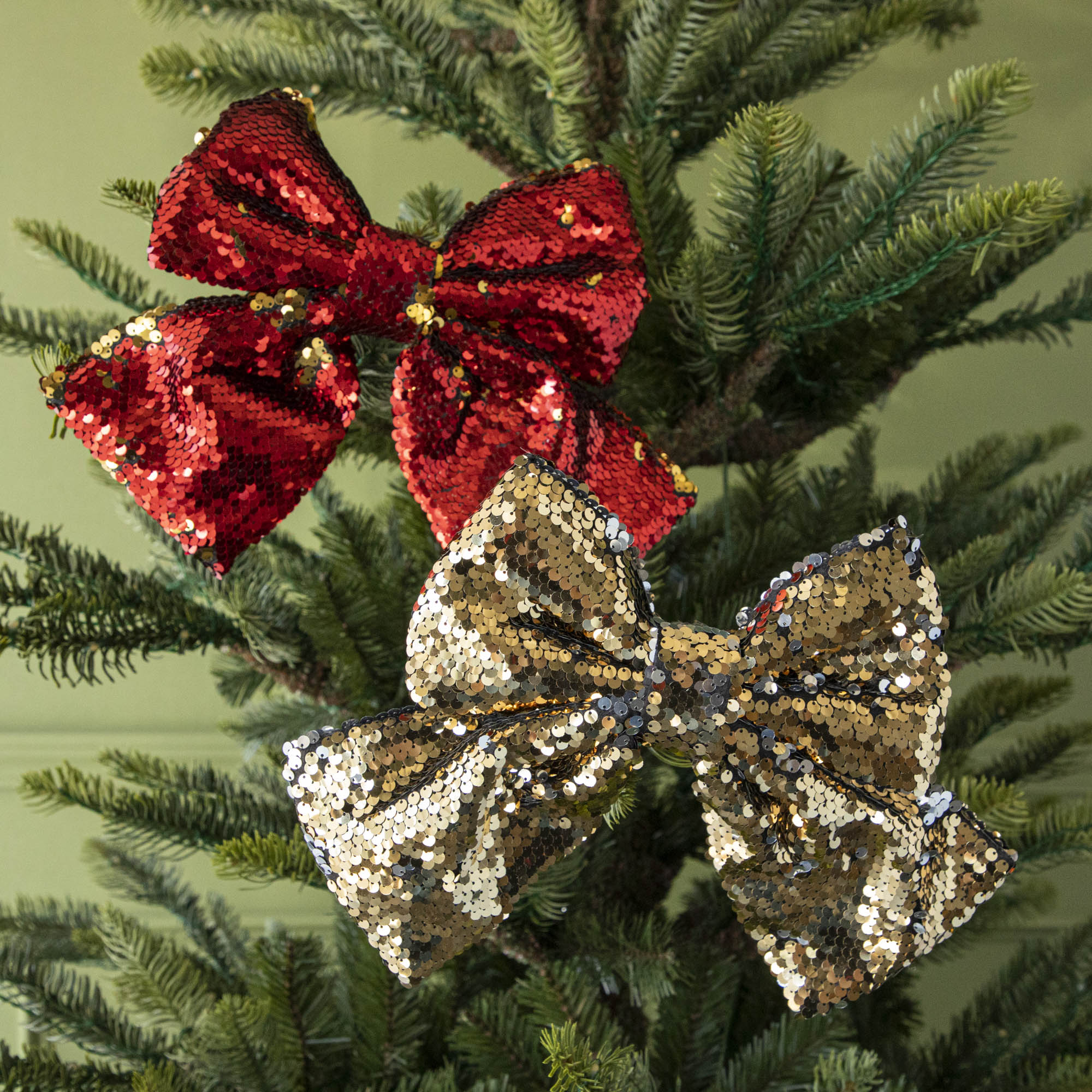 The red and gold Puffy Sequin Bows with Clip, clipped to a tree.