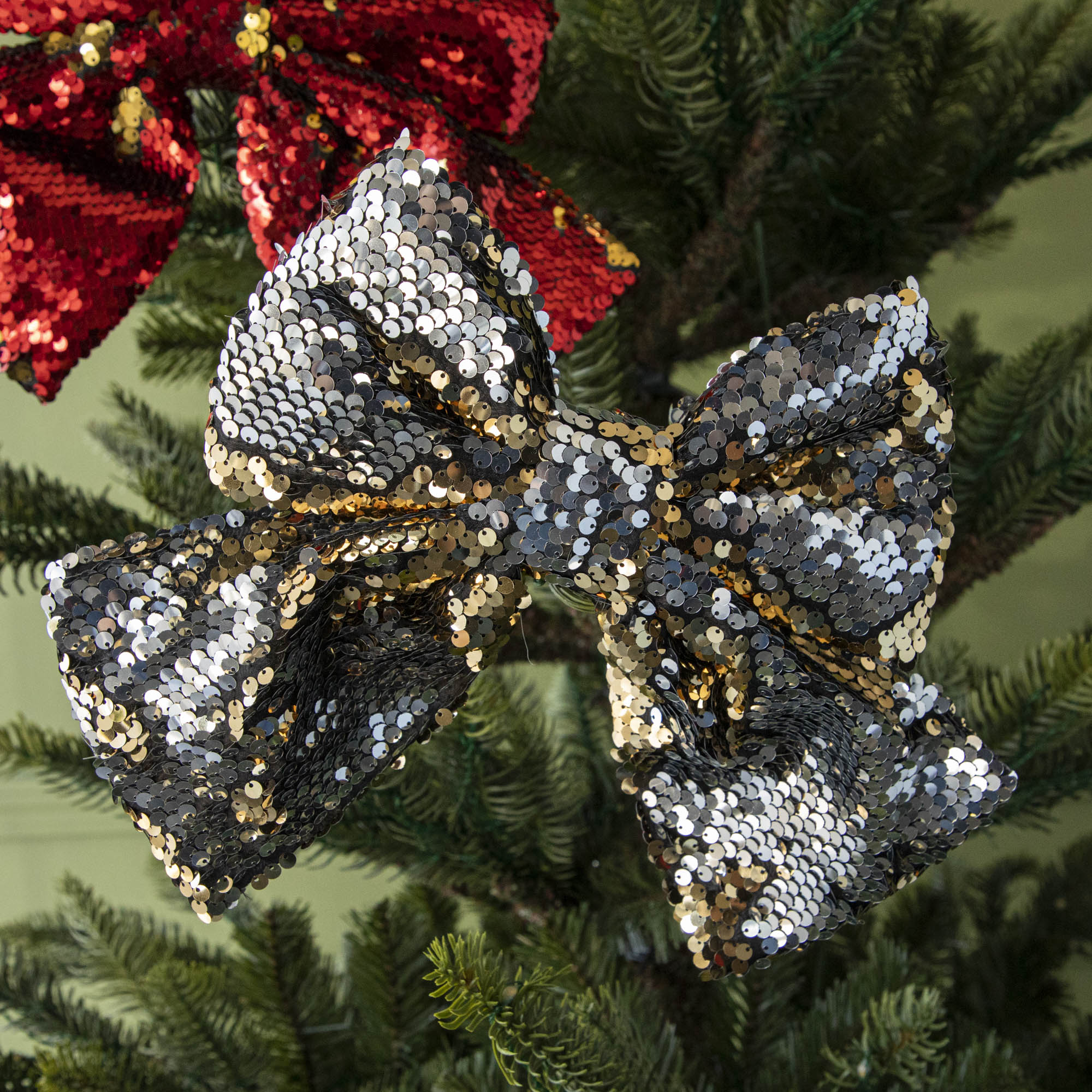 A close up of the gold Puffy Sequin Bow Ornament showing its reversible gold to silver sequins.