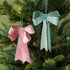 pink and green bow ornaments hanging in a tree