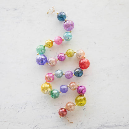 Colorful Shiny Stubble Ball Garland in a swirled shape on a marble table.