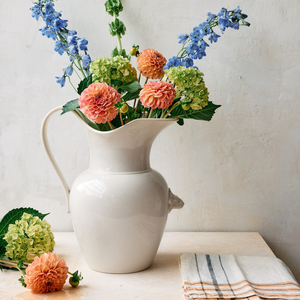 White vase with colorful flowers on a light surface.