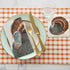 Top-down view of an elegant Thanksgiving place setting featuring a Heritage Turkey Guest Napkin on the plate and a Heritage Turkey Cocktail Napkin under a stemmed glass.