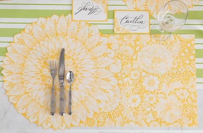 A bohemian-inspired place setting with a knife and fork, adorned with a Hester &amp; Cook Spring Bouquet Placemat featuring yellow and white accents.