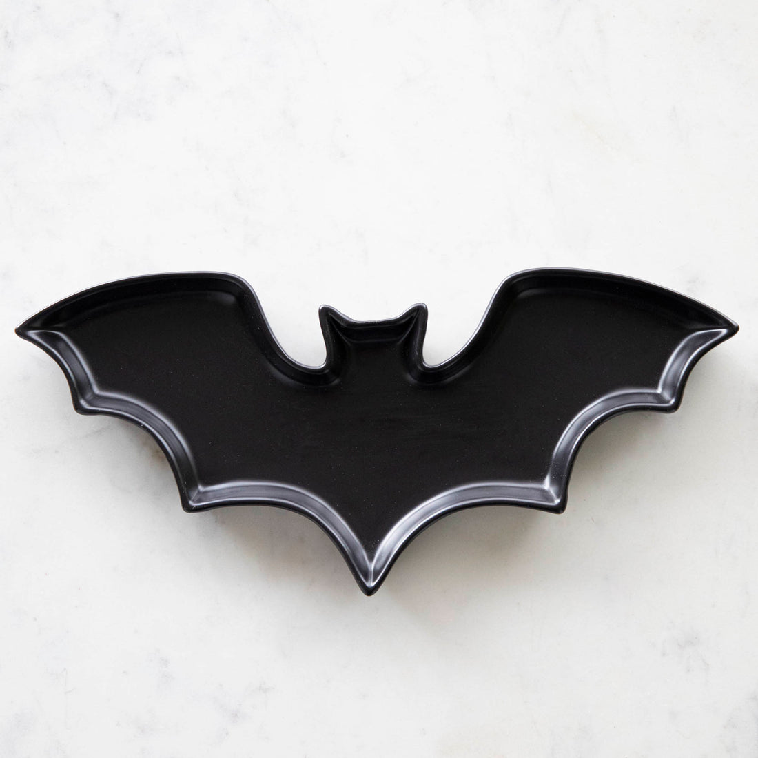 Black Stoneware Bat Shaped Plate  on a marble table.