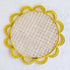 Iraca palm woven placemat with a neutral center and yellow scallops along the edge. 