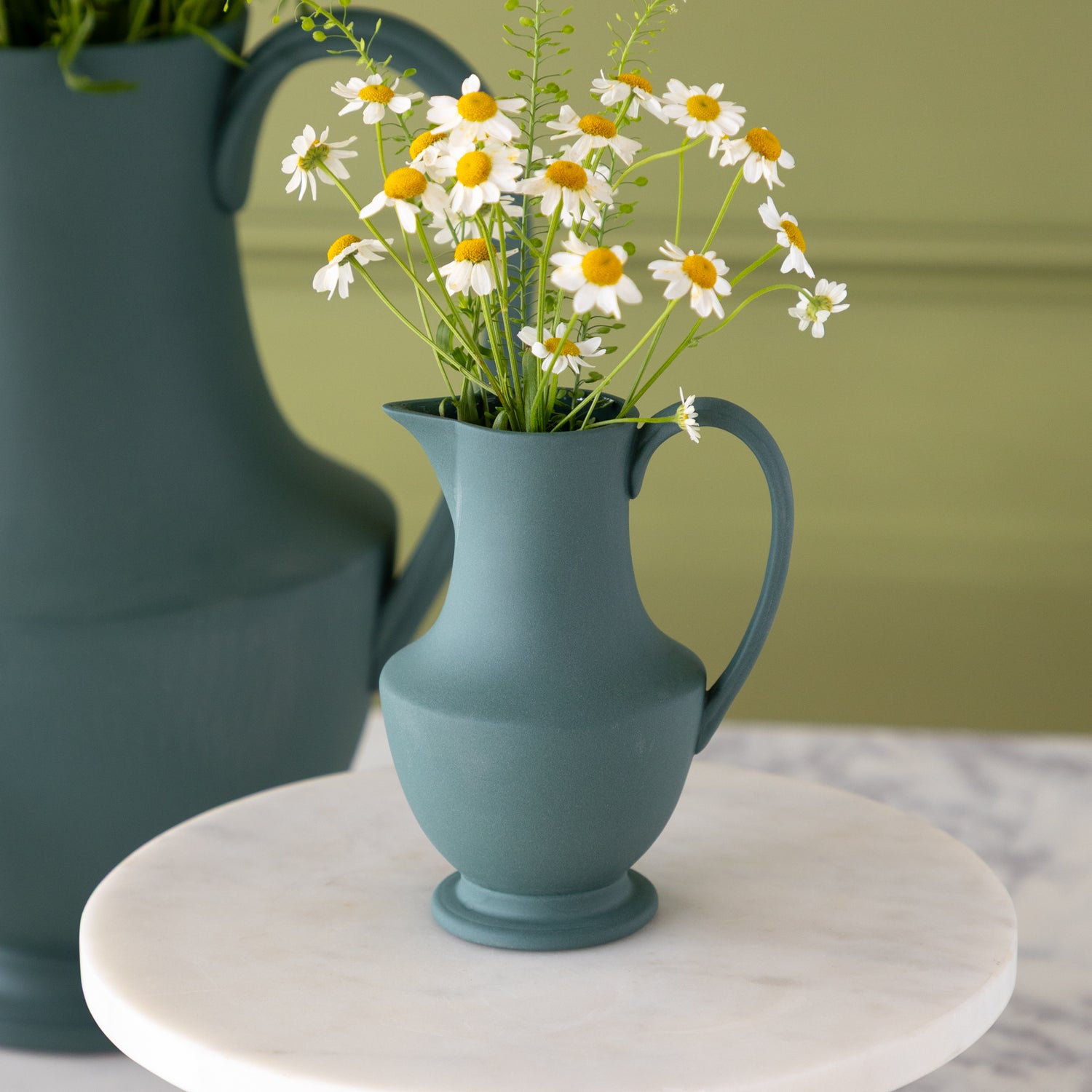 Toulouse Verdant Green Pitcher with flowers in it on a cake stand.