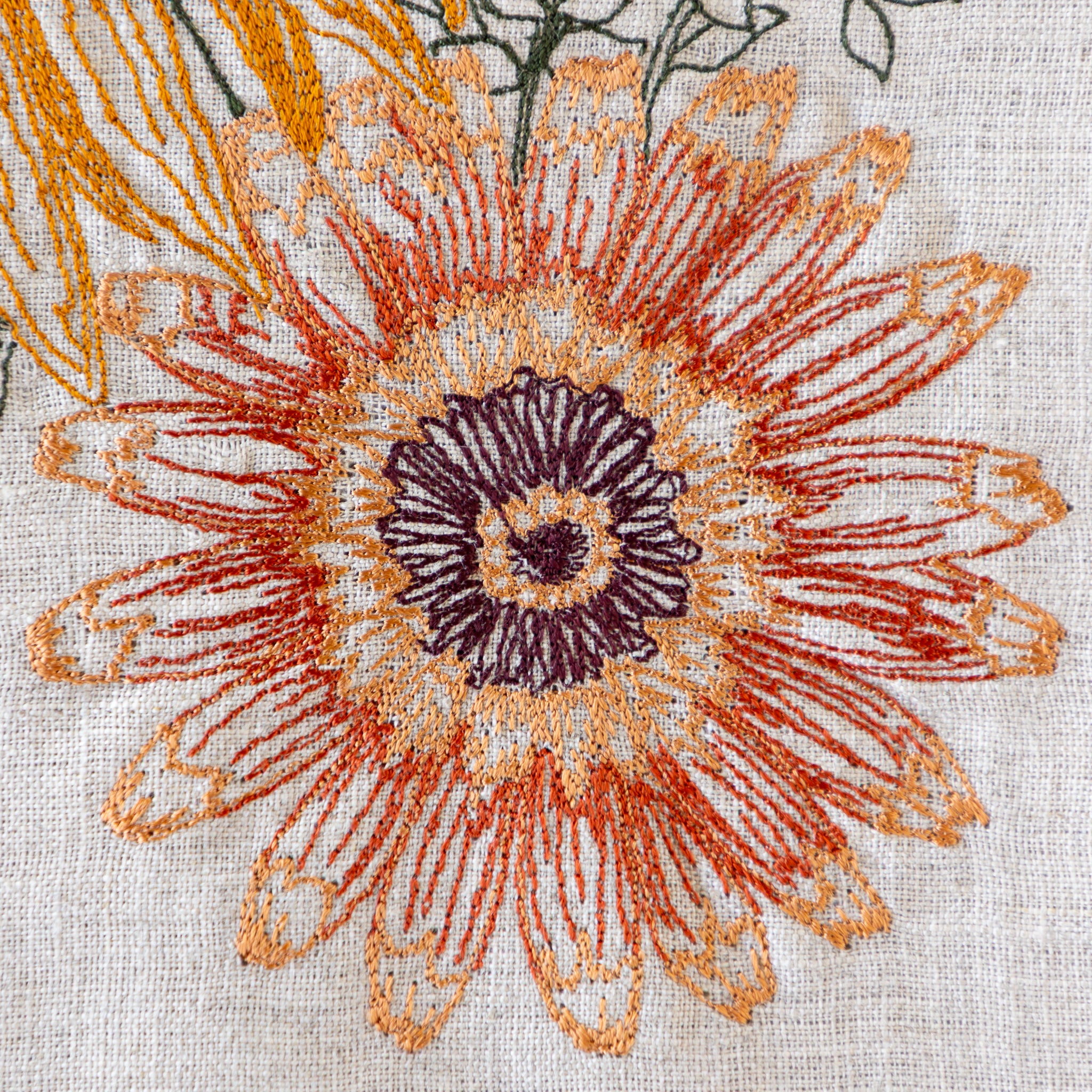 Close-up of a mum embroidery design on fabric with orange and purple colors.