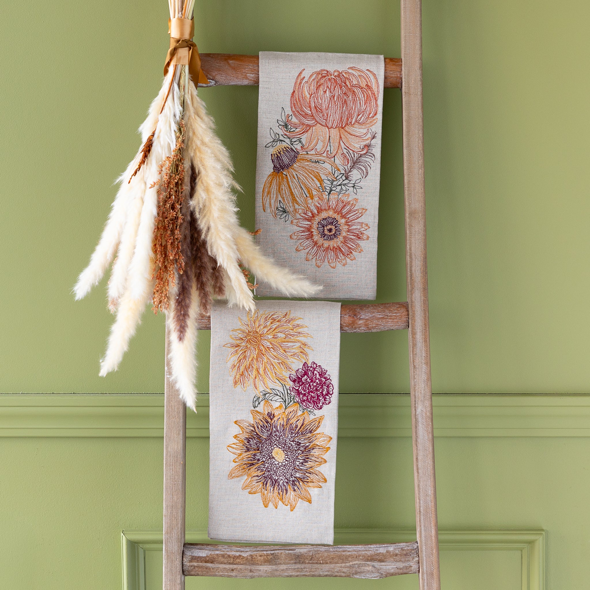Decorative towel with floral design on a wooden ladder against a green wall
