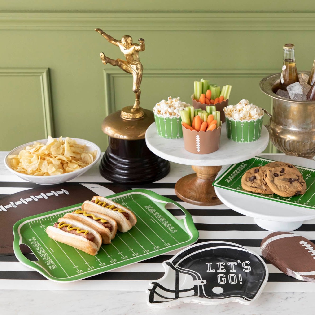 A football themed table setting with various snacks and football helmet and field plates.