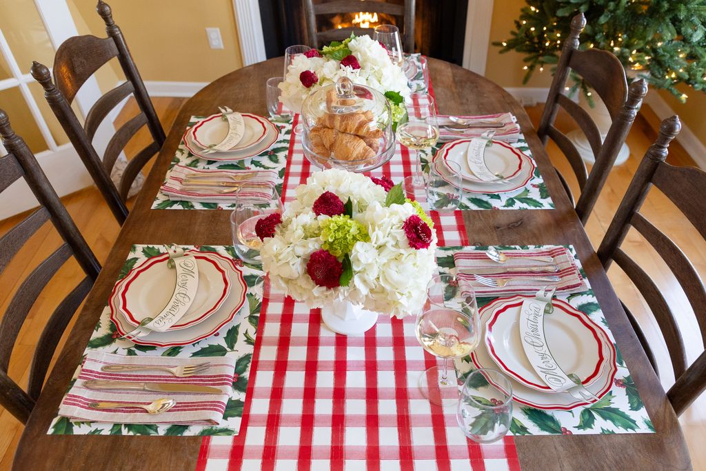 Decorated dining table with Christmas-themed place settings and centerpieces.