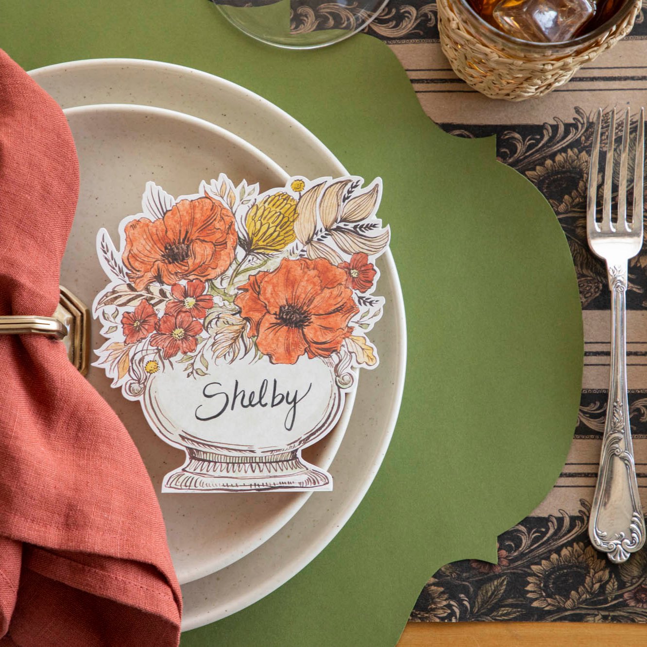 An elegant table setting with a Green French Frame placemat on a Vintage Sunflower stripe runner with cream dinner plates, a napkin and Autumn Arrangement Place card on the plates.