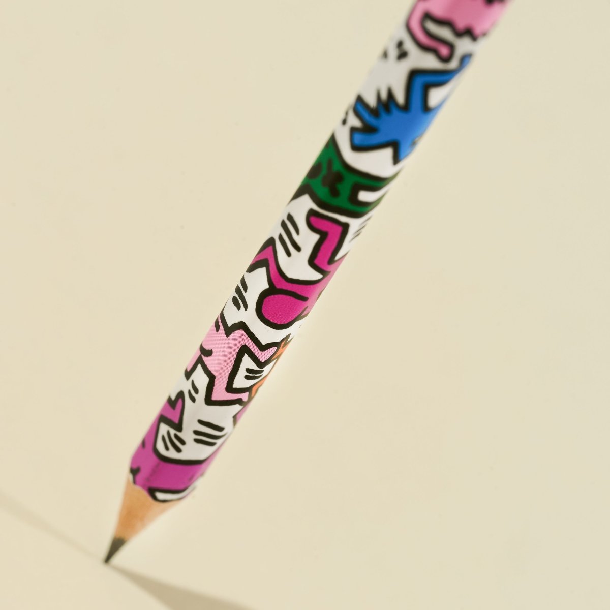Blackwing Volumes pencil with colorful artwork by Keith Haring on a beige background.